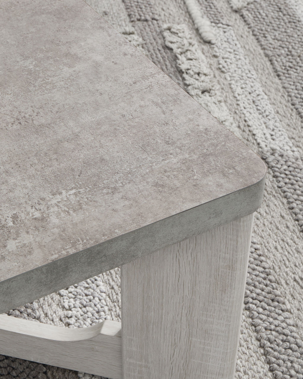 Occasional table with textured gray top and whitewash open side supports