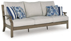 Light gray sofa with two blue patterned throw pillows and striped cushions, dark wood frame