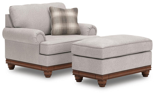Beige upholstered loveseat with ottoman, plaid pillows, rounded arms, dark wood legs