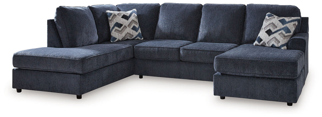 Blue sectional sofa with ottoman, low arms and patterned throw pillows