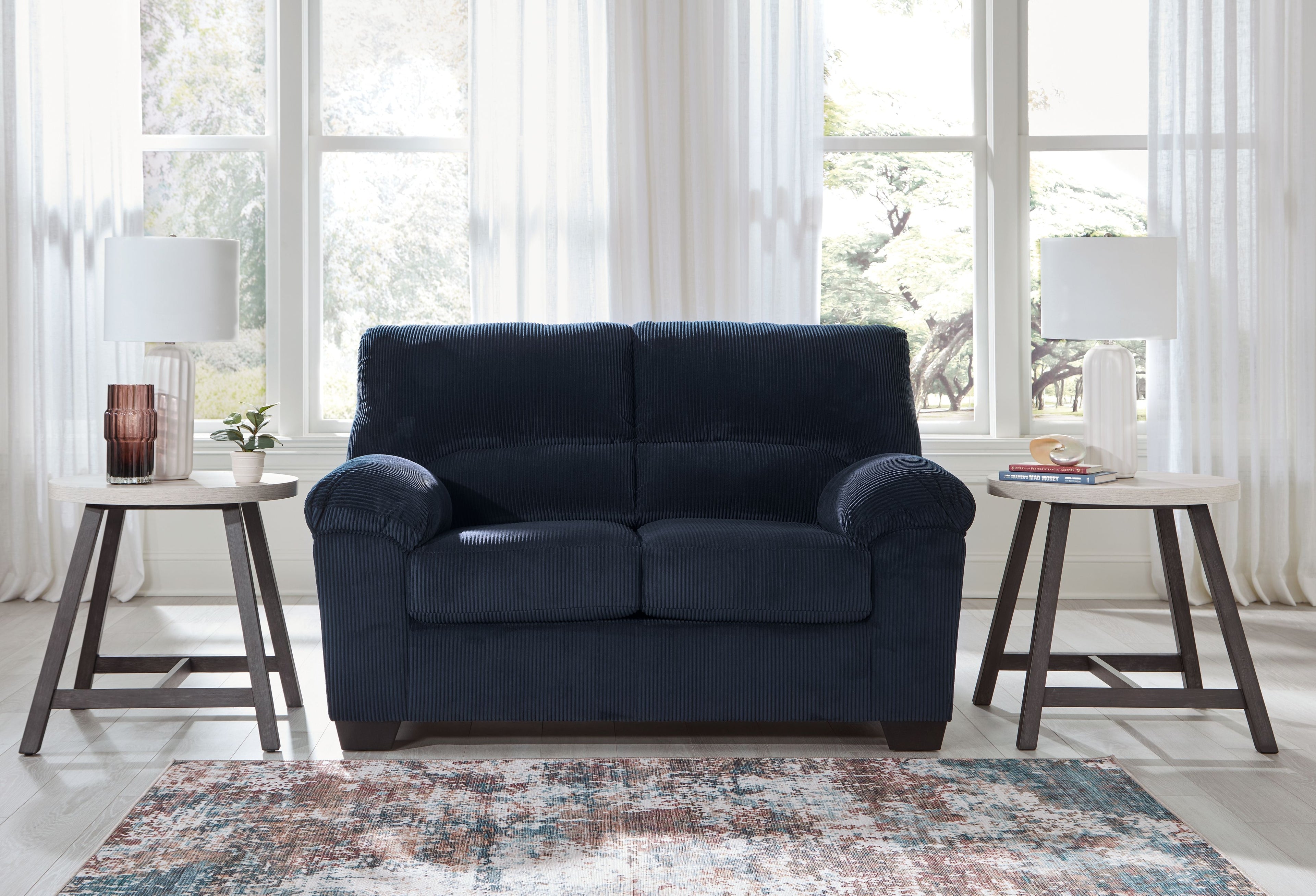 Navy corduroy loveseat with rolled arms, two-seat cushions, and dark wood feet