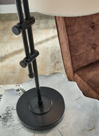 Black round base and vertical metal pole of a floor lamp with fabric shade