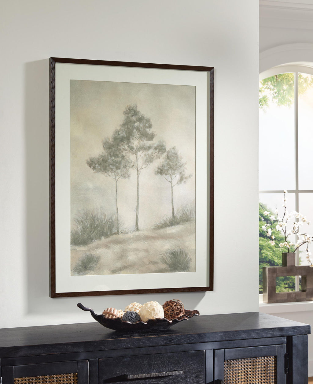 Dark wood-framed landscape wall art with three trees and foggy field