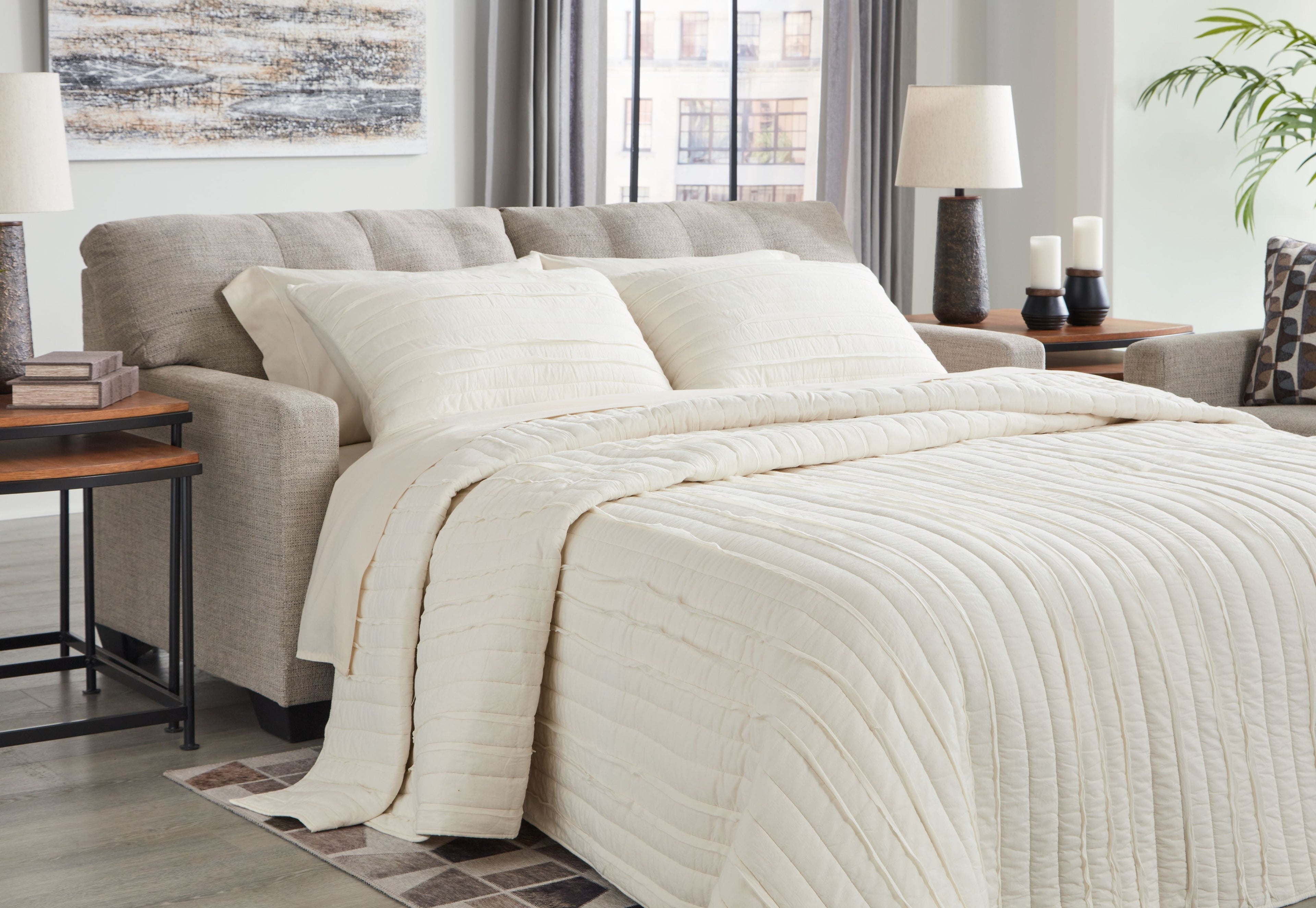 Pebble sofa sleeper with an extended bed and layered white bedding