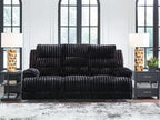 Black corduroy reclining sofa with rolled arms and deep, tufted cushions