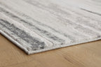 Gray rug corner detail with low pile and distressed stripe pattern