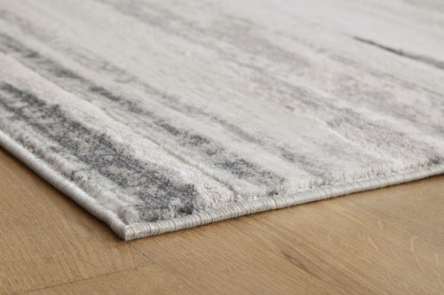 Gray rug corner detail with low pile and distressed stripe pattern