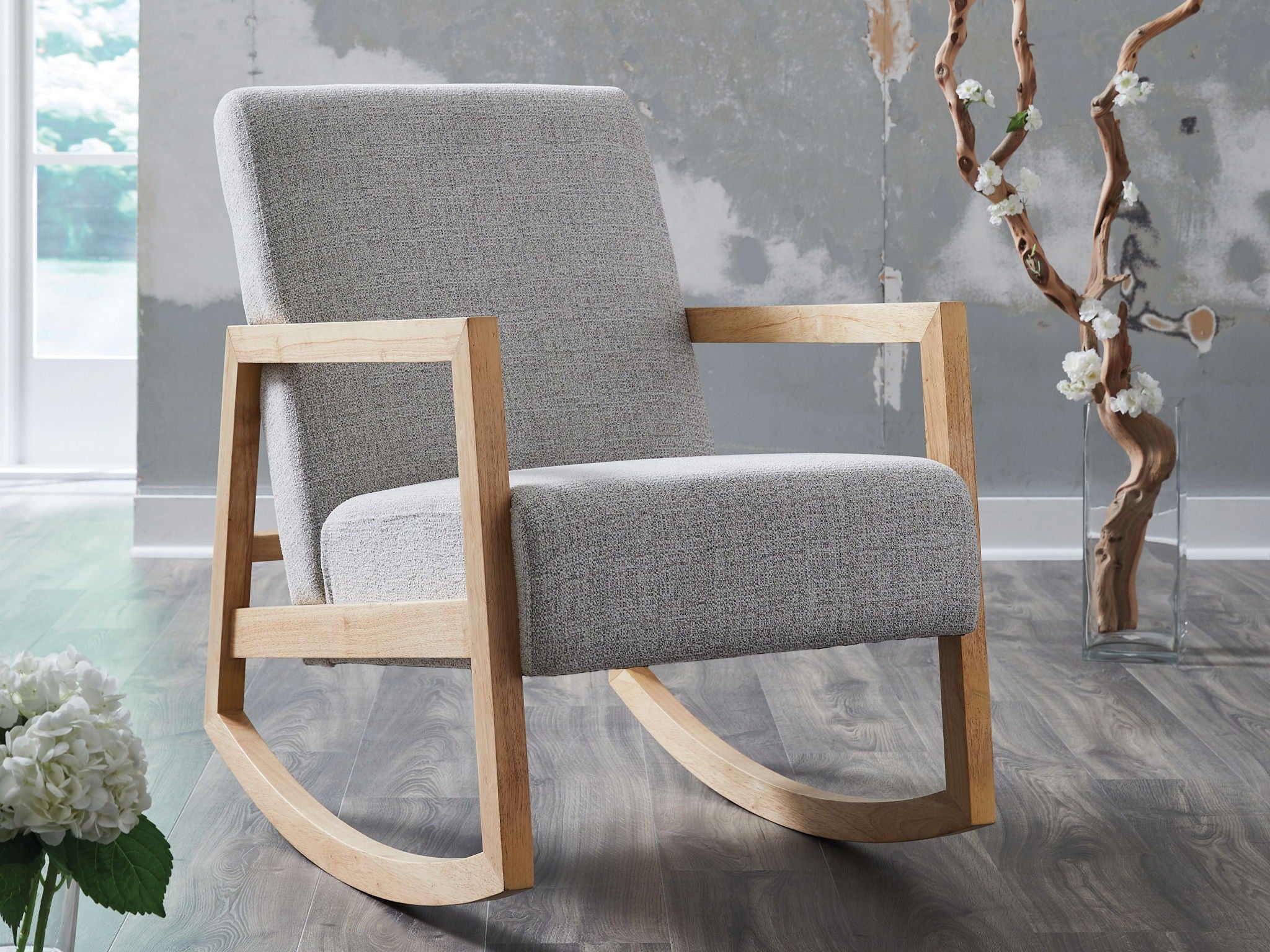 Gray fabric accent chair with light wood arms and curved rocker base