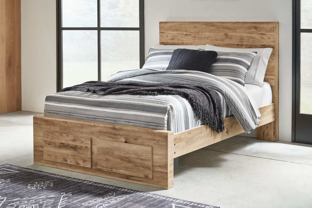Storage bed with two drawers, light beige wood, black and gray striped bedding and pillows