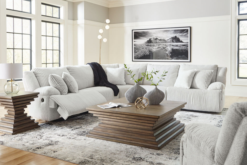 Light gray reclining sectional sofa with chaise and patterned accent pillows