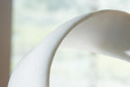 White sculpture close-up showing curved arch-like opening and smooth surface.