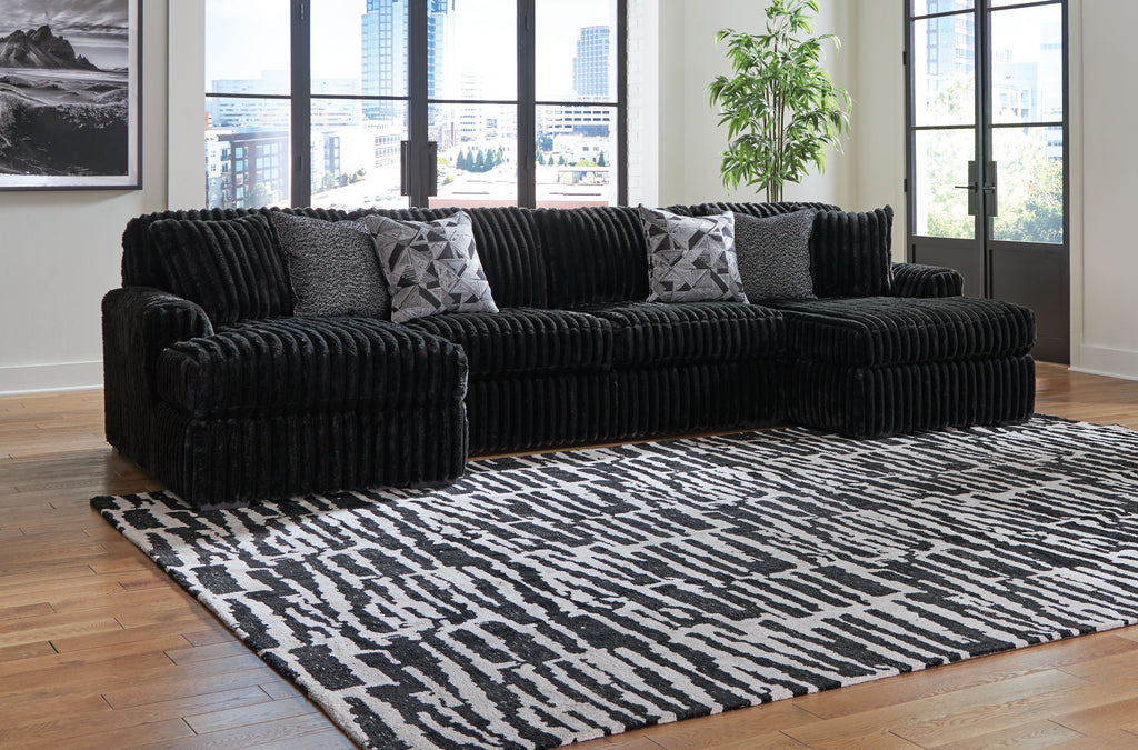 Black sectional sofa with chaise and ribbed texture, with patterned throw pillows