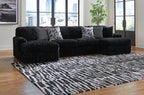 Black sectional sofa with chaise and ribbed texture, with patterned throw pillows