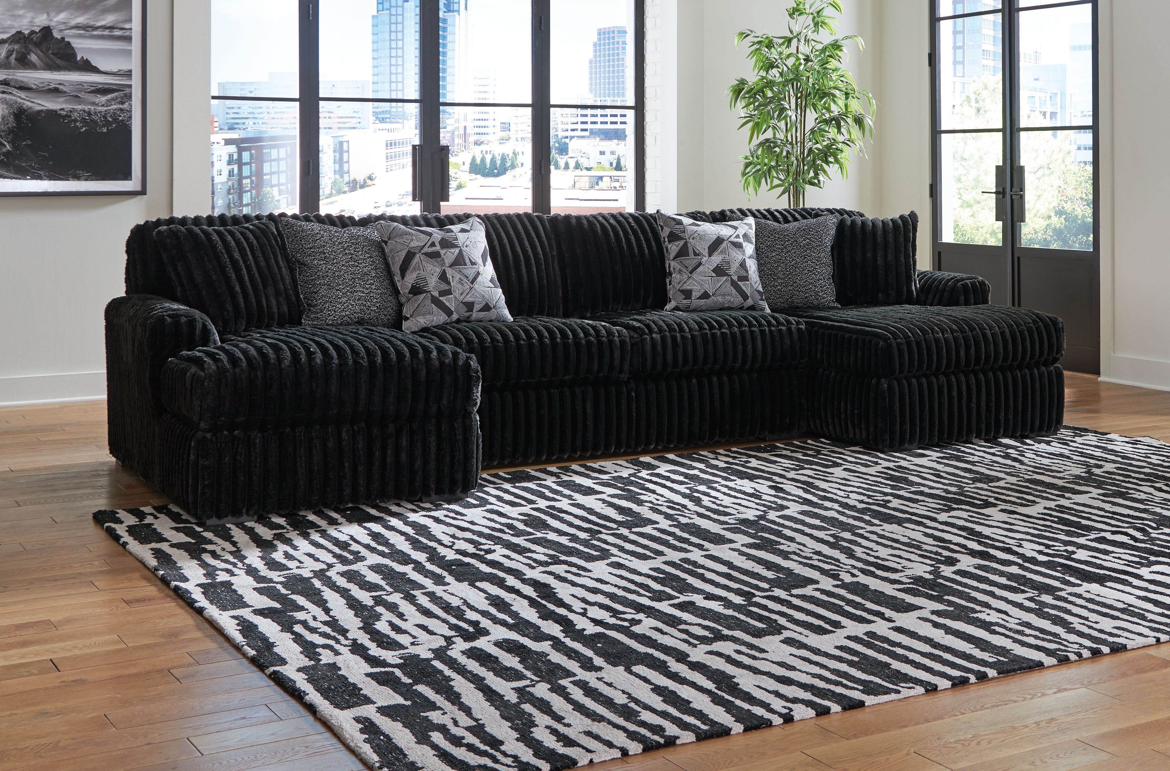 Black sectional sofa with chaise and ribbed texture, with patterned throw pillows