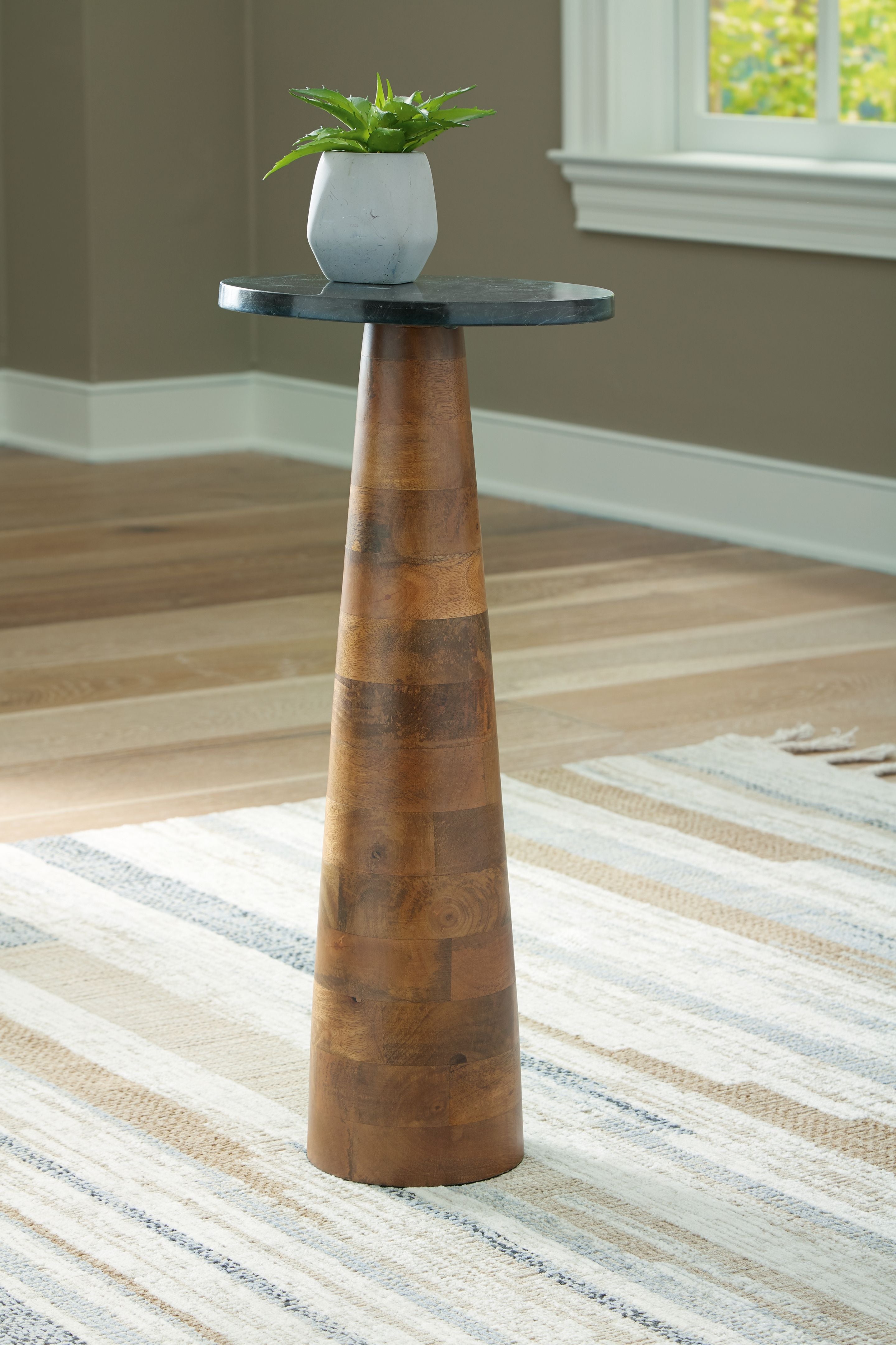Round black stone-look accent table with narrow pedestal base in brown wood