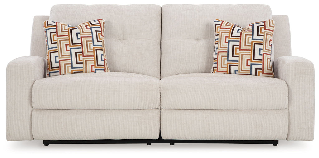 Beige reclining sofa with split back and patterned square throw pillows