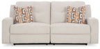 Beige reclining sofa with split back and patterned square throw pillows