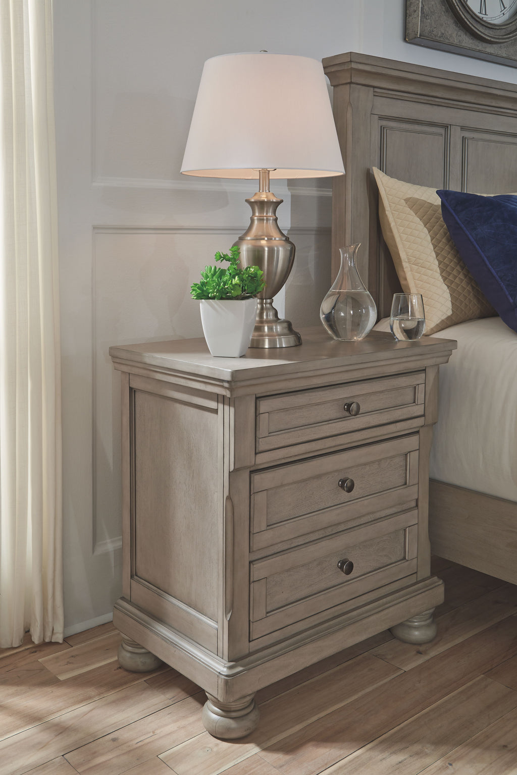 Three-drawer light gray nightstand with brass-tone lamp base