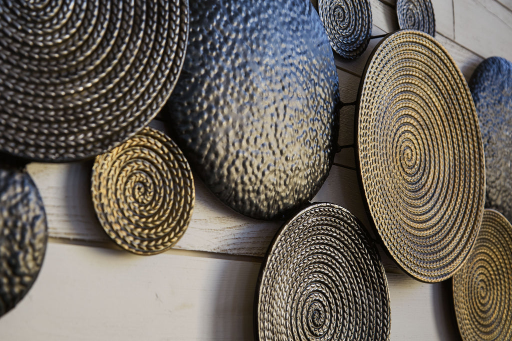 Close-up of metallic woven circular wall decor discs in dark gray and bronze.