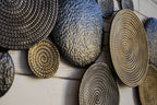 Close-up of metallic woven circular wall decor discs in dark gray and bronze.