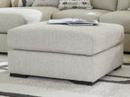 Oversized accent ottoman with thick cushion and dark legs, light pebble woven upholstery.