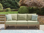 Outdoor sofa with light-green seat cushions, two striped pillows, and beige frame
