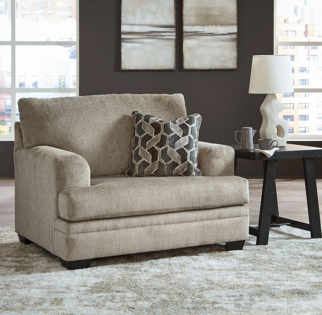 Beige chair-and-a-half armchair with geometric throw pillow and upholstered cushions