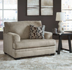 Beige chair-and-a-half armchair with geometric throw pillow and upholstered cushions