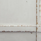 Chipped white finish detail on TV stand panel with distressed edges