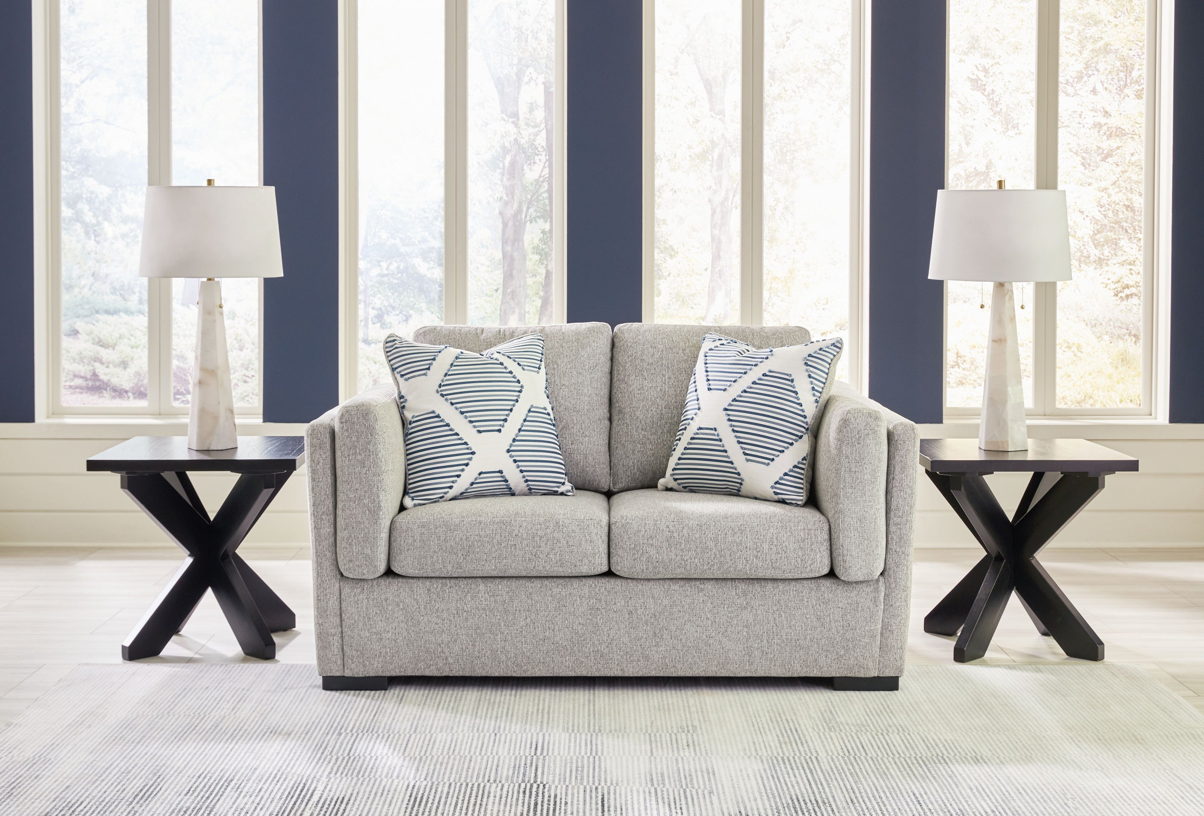 Gray loveseat sofa with two white-and-blue striped throw pillows