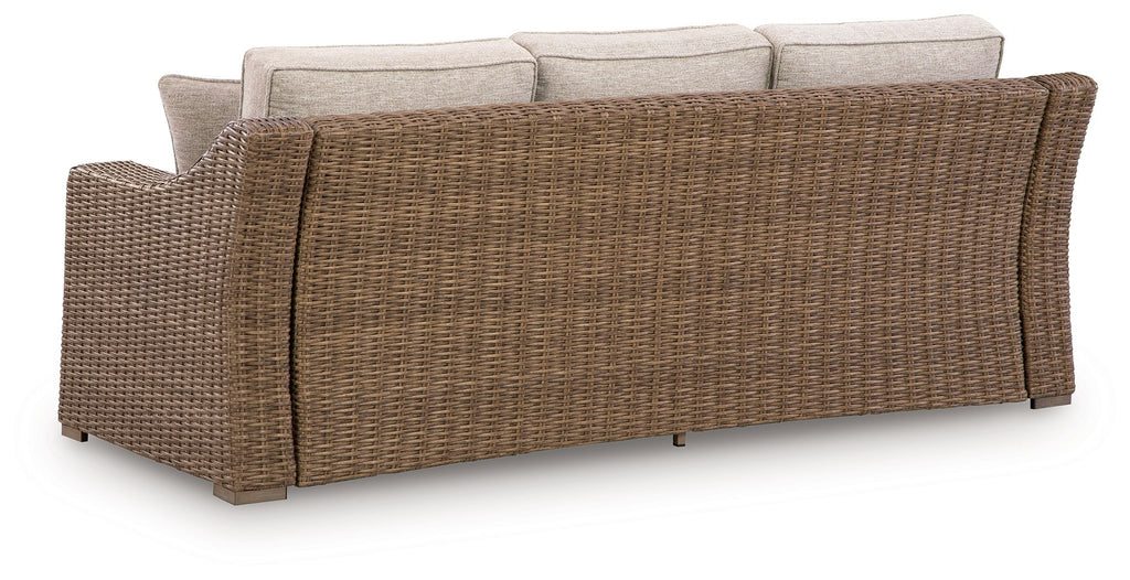 Beige sofa with woven wicker sides and back, three cushioned seats
