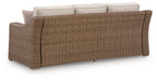 Beige sofa with woven wicker sides and back, three cushioned seats