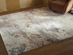 Distressed abstract area rug in beige and gray with rust spots