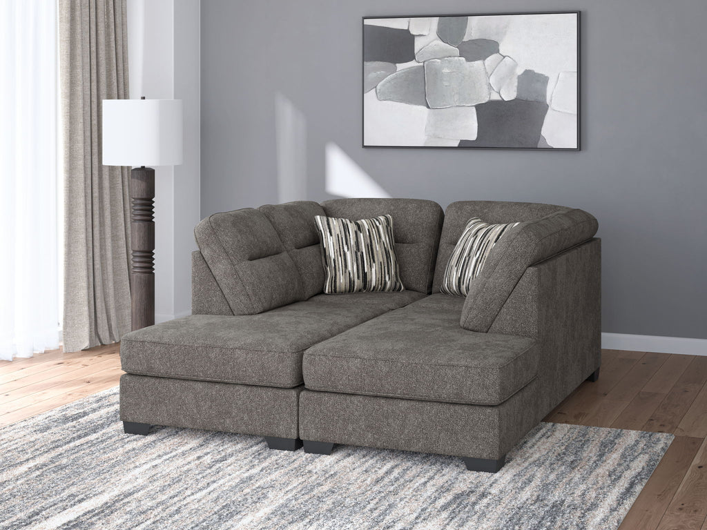 Dark gray chaise sectional with tufted cushions and two striped pillows, styled in a living room