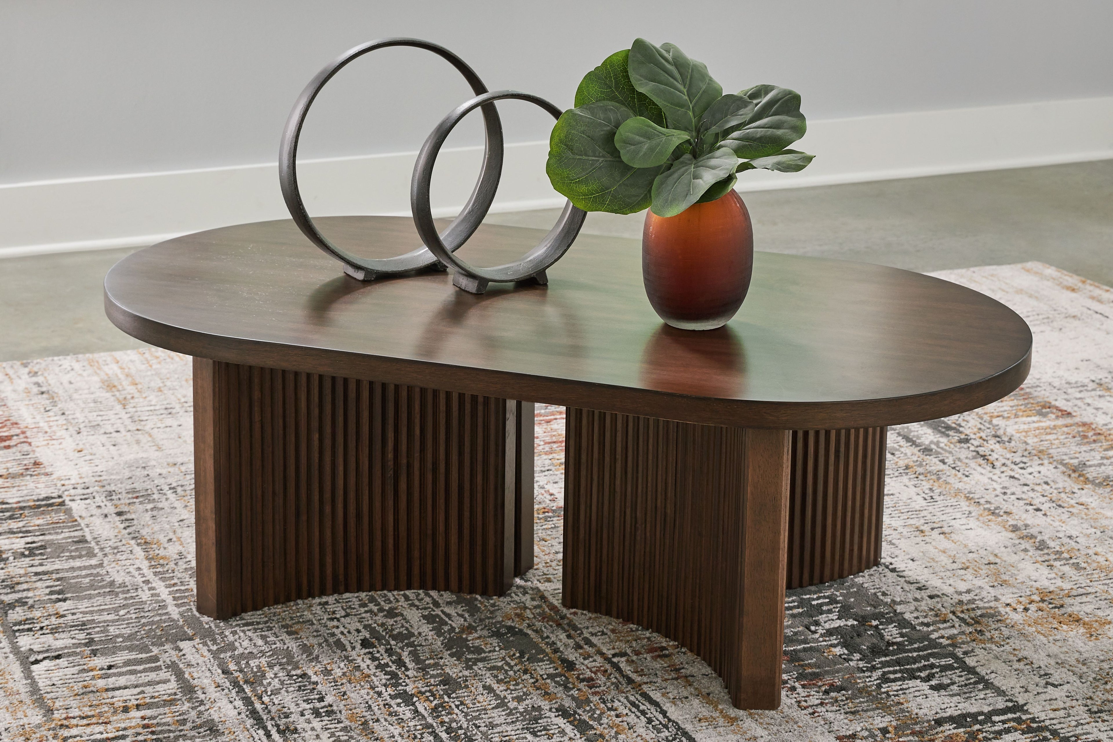 Oval dark brown cocktail table with ribbed base and flat oval tabletop