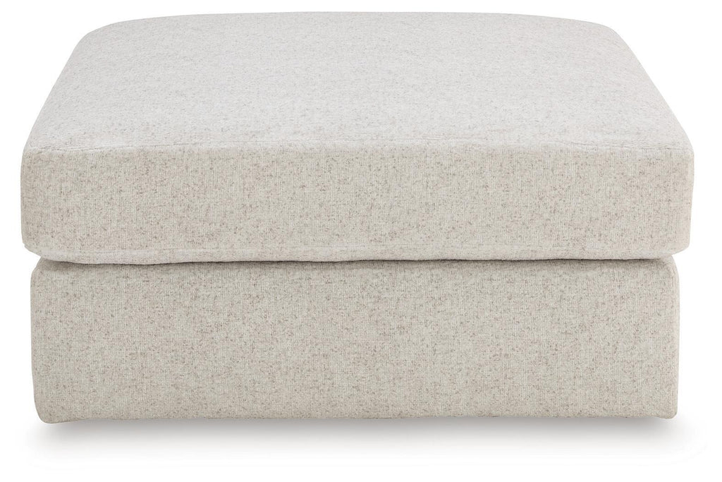 Beige upholstered ottoman with smooth rounded top and thick, padded sides