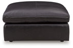Black oversized accent ottoman with stitched top edge, rounded cushion, and visible legs