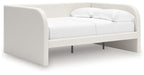 Upholstered day bed in beige fabric with white cushions; open underside with legs