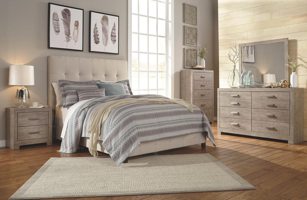 Gray upholstered queen bed with tufted headboard, patterned quilt, and pillows
