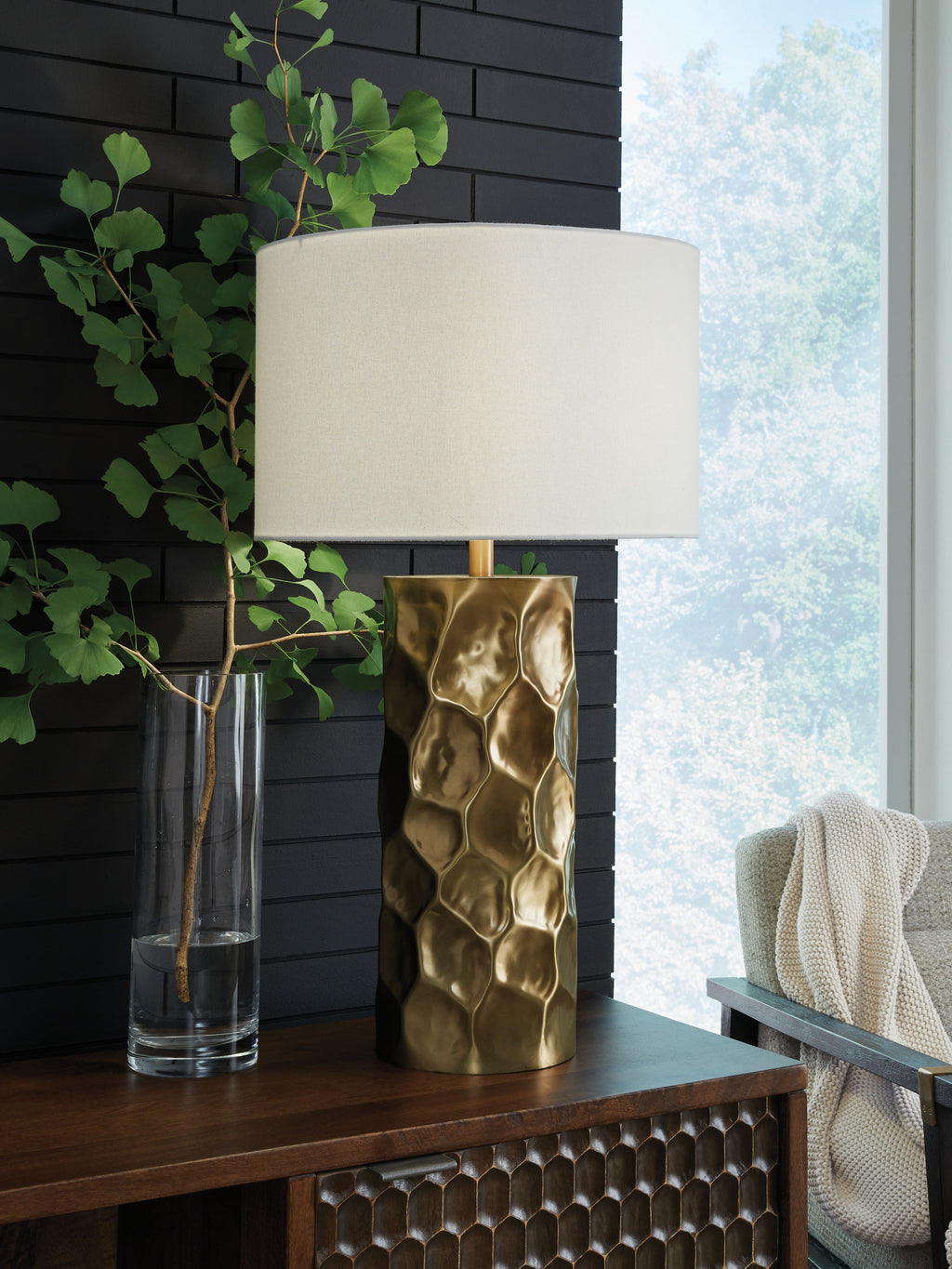 Gold metal table lamp with white drum shade and hammered, faceted body
