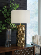Gold metal table lamp with white drum shade and hammered, faceted body