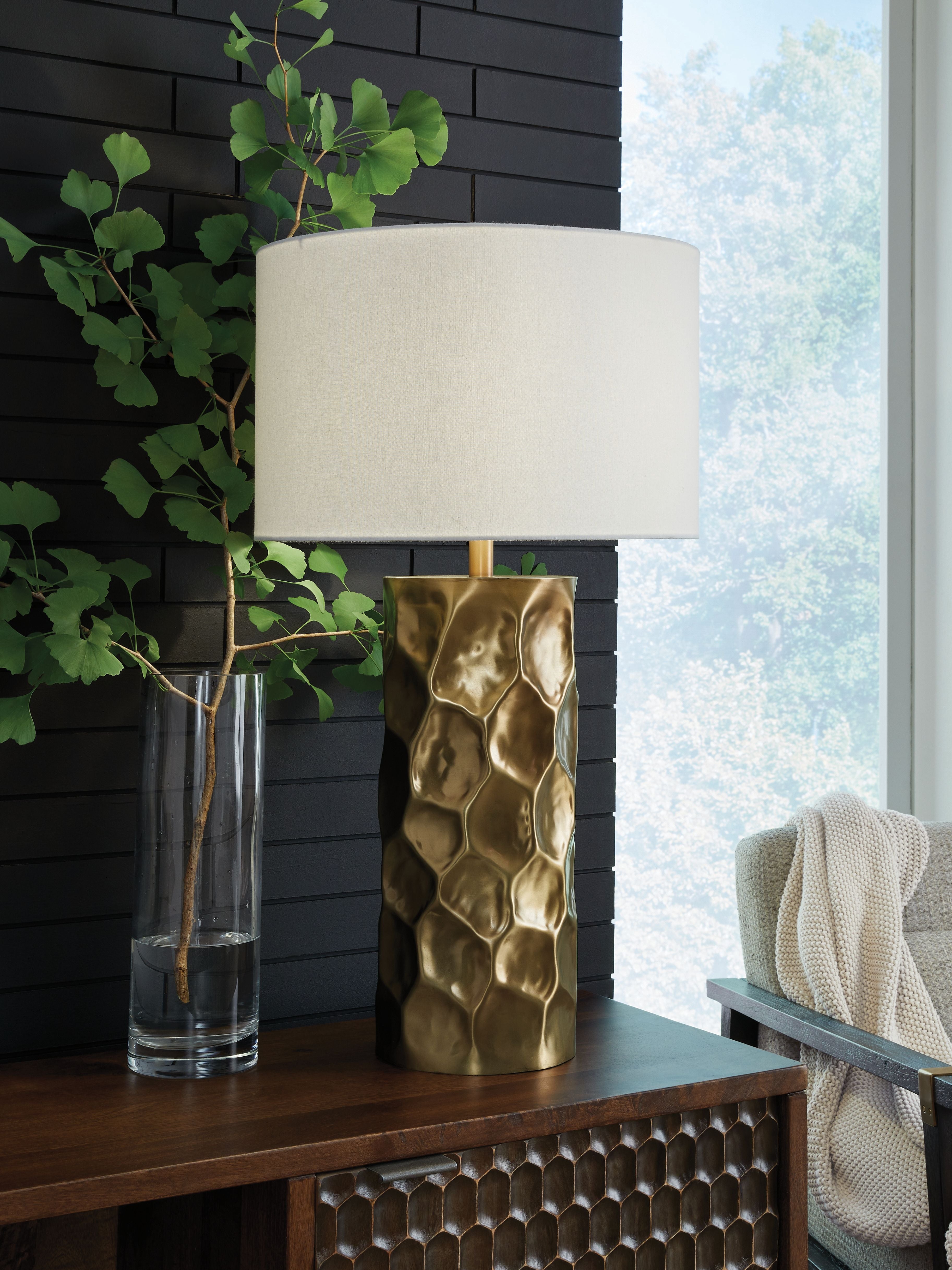 Gold metal table lamp with white drum shade and hammered, faceted body