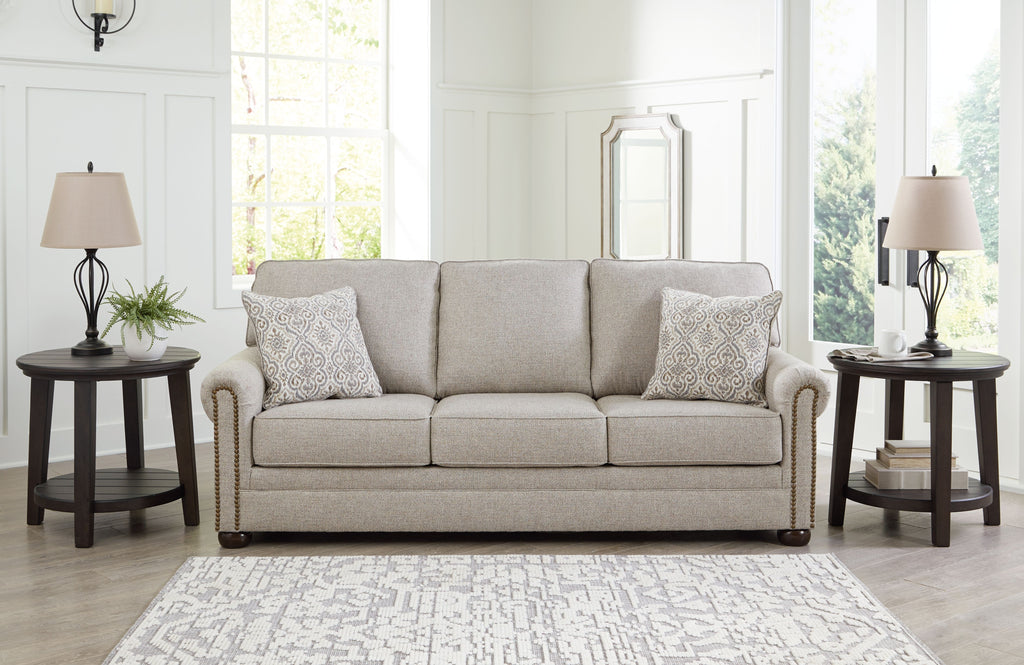 Light gray sofa with rolled arms and three decorative pillows, including patterned accents