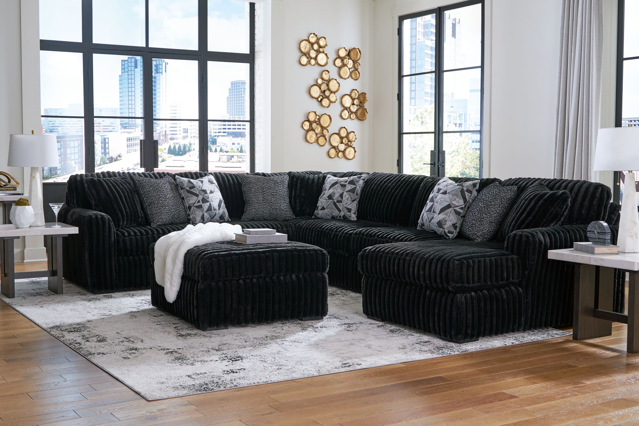 Black sectional sofa arrangement with chaise, ottoman seats, and textured pillows