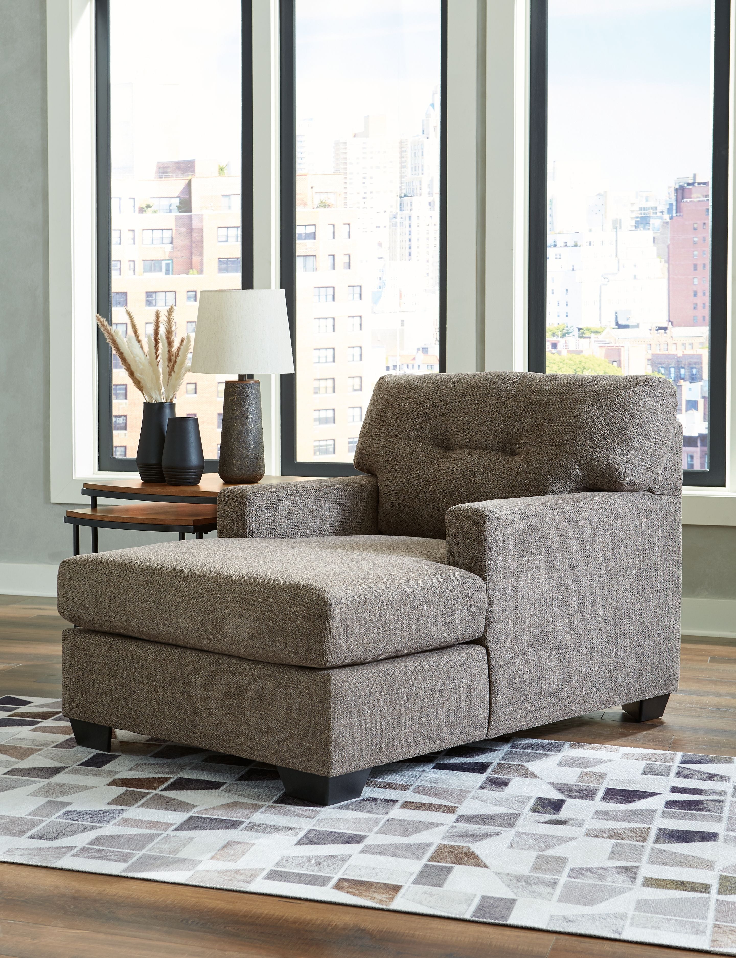 Dark brown chaise lounge chair with tufted backrest, padded seat, and black feet