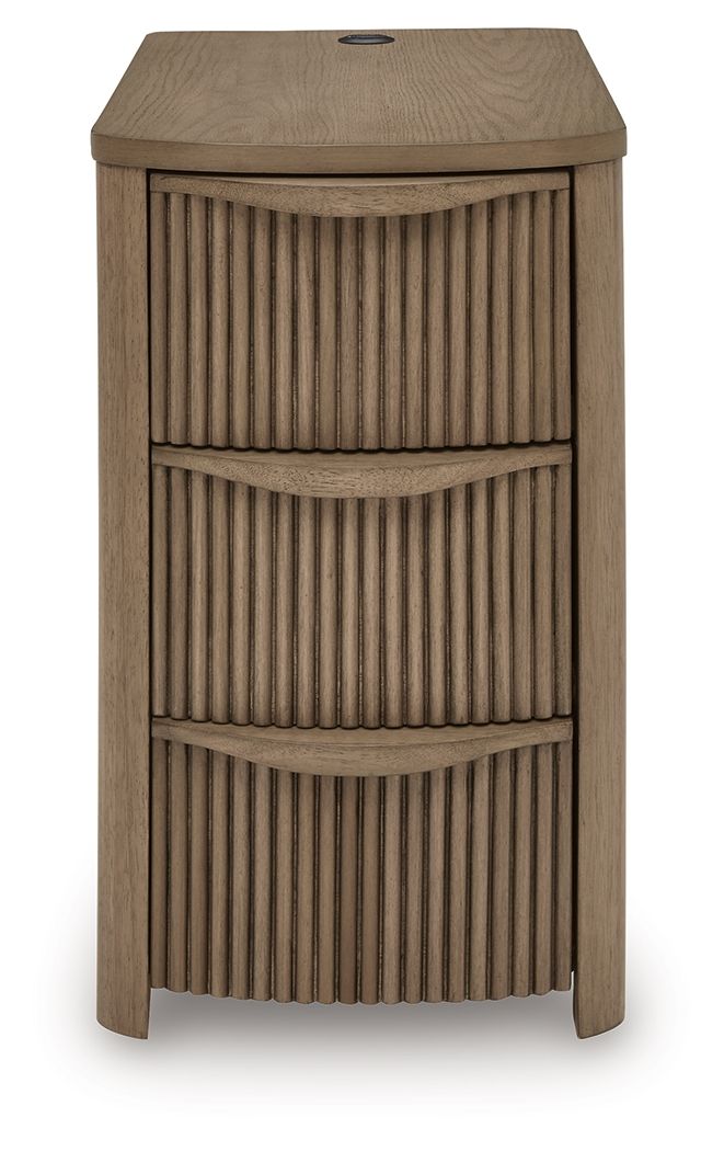 Light brown chair side end table with vertical slat panels and three drawer compartments