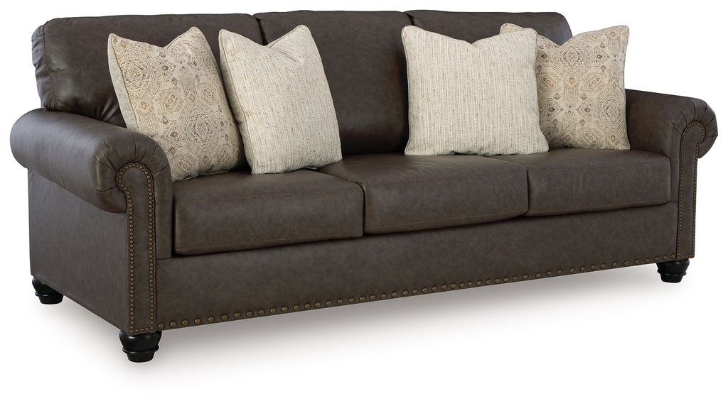Dark brown upholstered sofa with three seat cushions and patterned throw pillows.