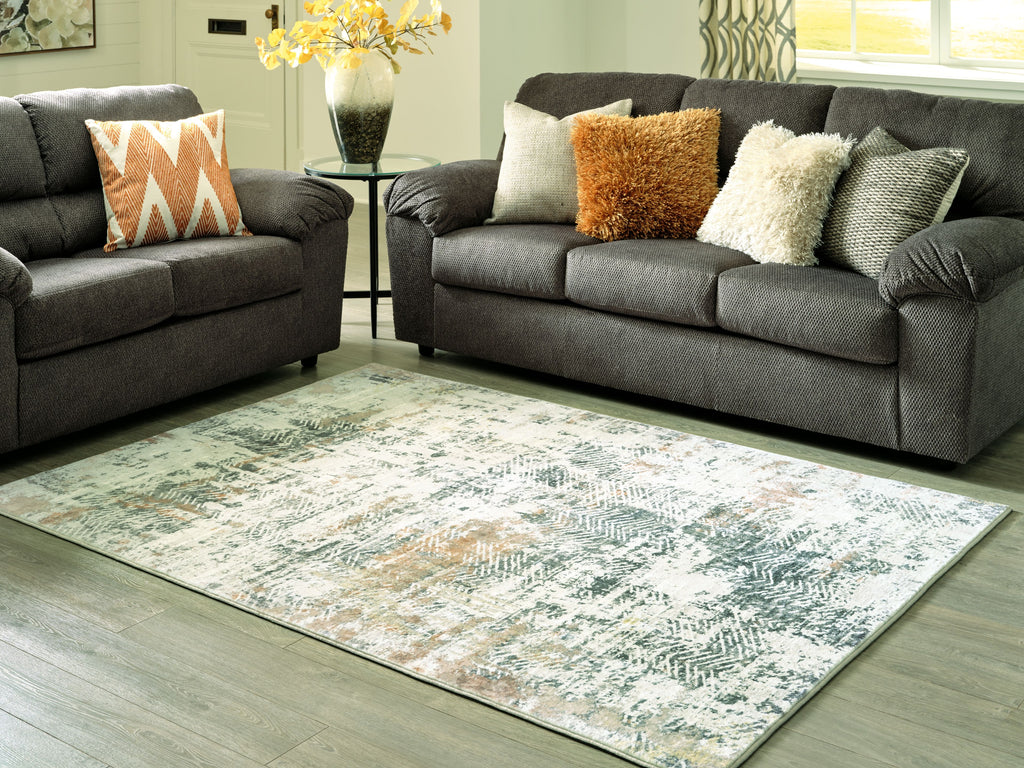 Abstract area rug with light gray and teal tones on living room floor