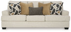 Light beige sofa with patterned pillows and tan and dark gray cushions on seats