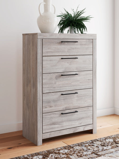 Gray five-drawer chest with dark bar handles and light woodgrain finish